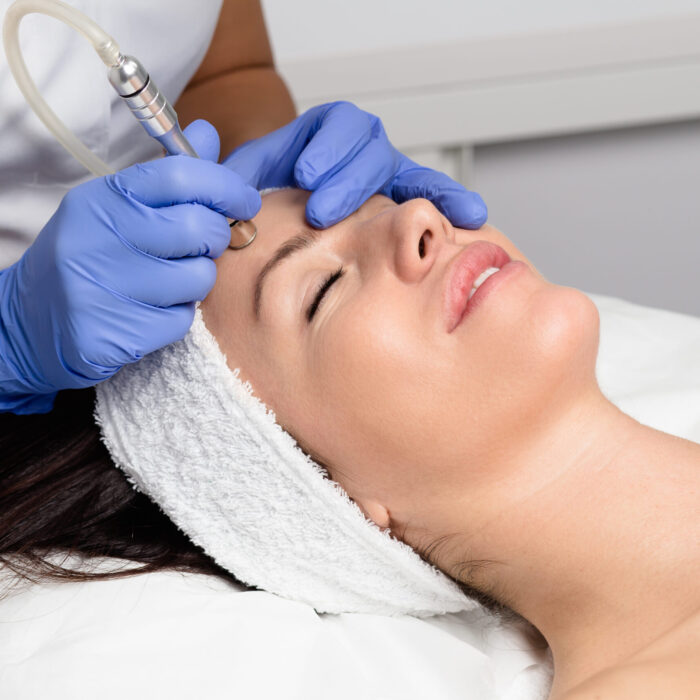 Beautiful woman getting facial microdermabrasion peeling treatment at luxury cosmetic beauty spa clinic. Exfoliation, rejuvenation and hydratation. Cosmetology concept.
